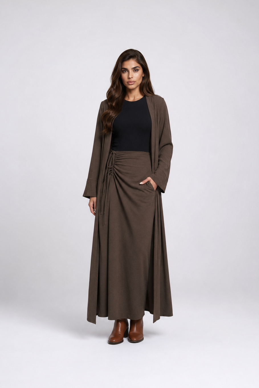 A woman modeling a dark brown long-sleeve wrap maxi skirt with a matching open-front cardigan, worn over a black top and brown ankle boots, against a light gray studio background.