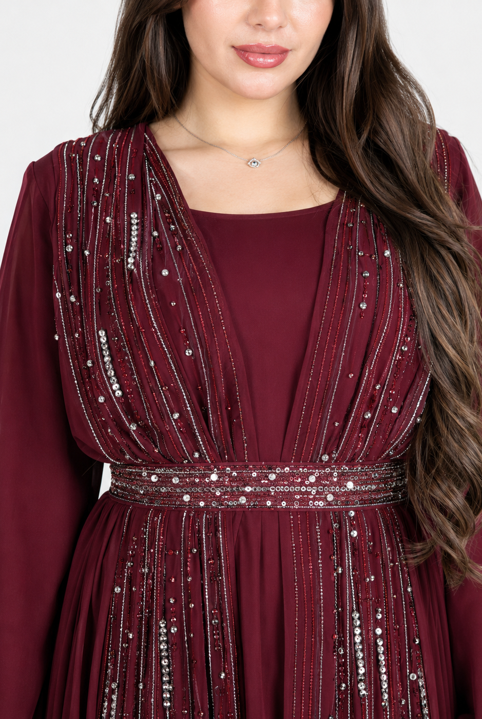 A close-up of a woman wearing a deep burgundy long-sleeve dress with silver beaded vertical stripes and a matching beaded waistband.