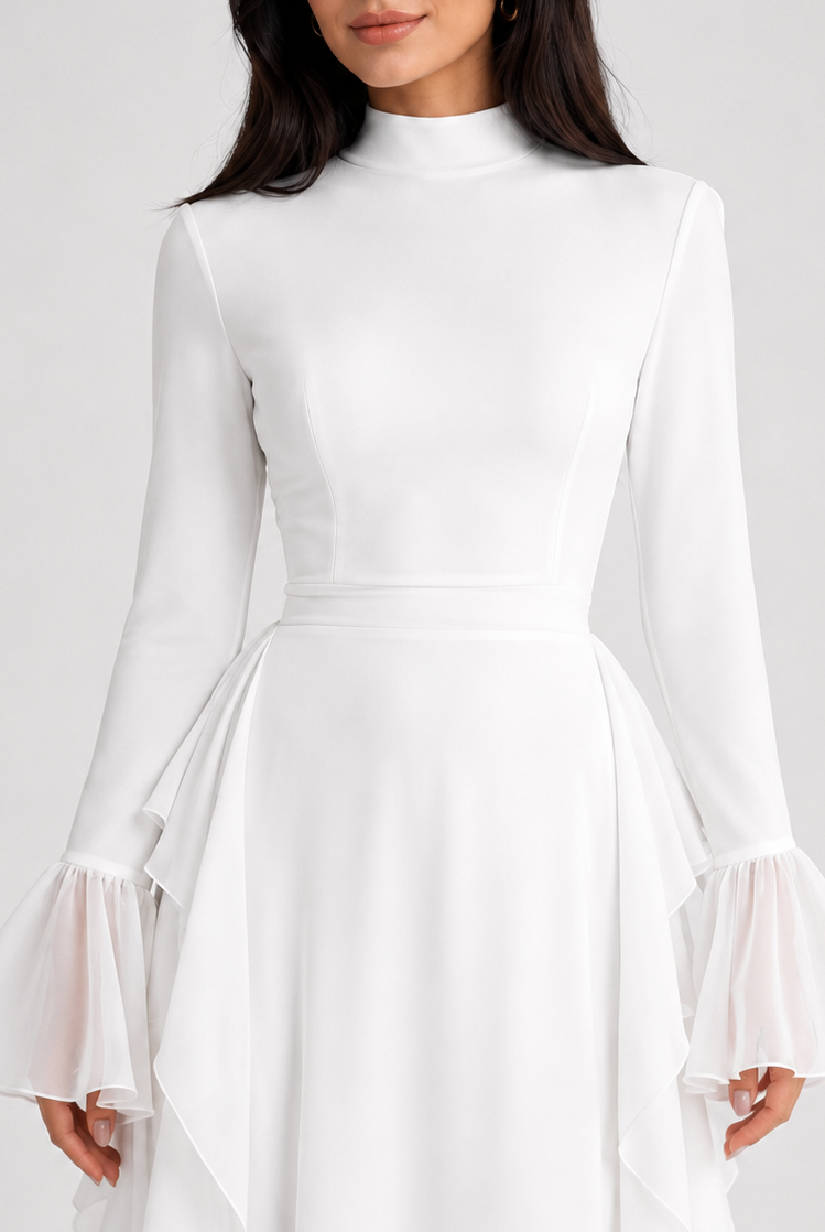 A woman wearing a white long-sleeve mock-neck dress with flared bell sleeves and a high-low layered hem, photographed against a light gray studio background.