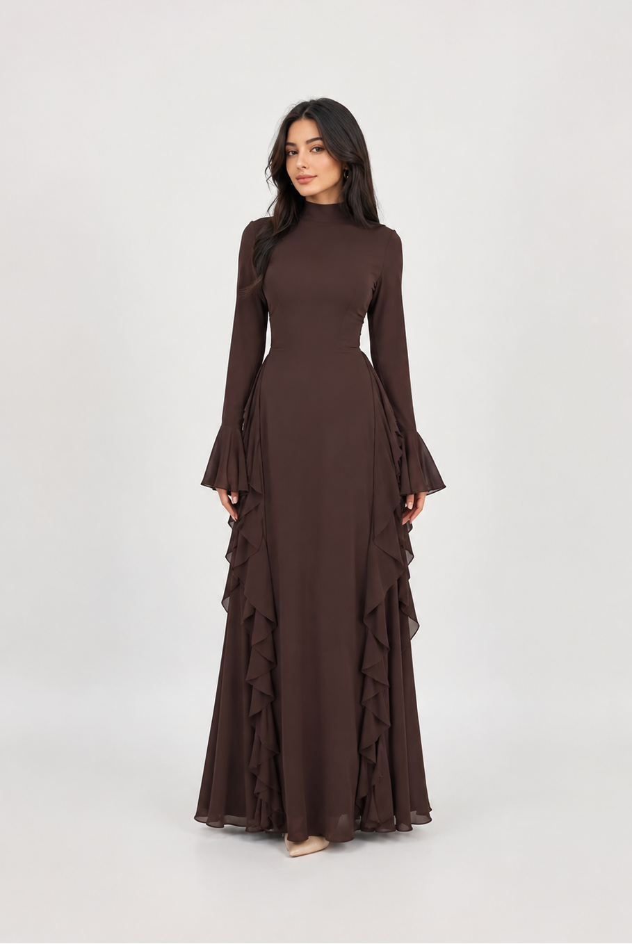A woman modeling a long-sleeved, high-neck maxi dress in a solid dark brown color, featuring flared bell sleeves and a tiered ruffle skirt, set against a plain light gray studio background.