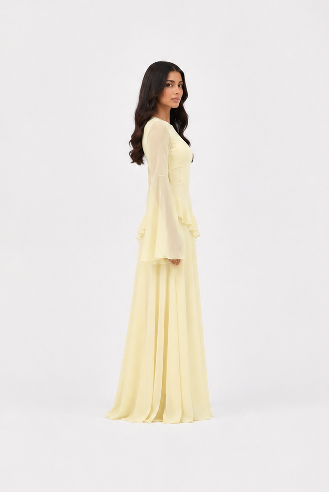 A woman modeling a long-sleeved, floor-length pale yellow dress, shown from the back against a seamless white studio background.