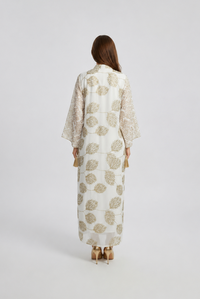 Woman wearing a long, light-colored dress with a floral pattern on a white background
