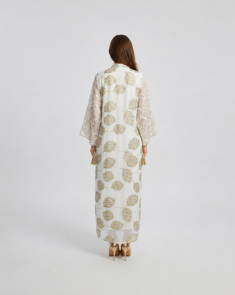 Woman wearing a long, light-colored dress with a floral pattern on a white background