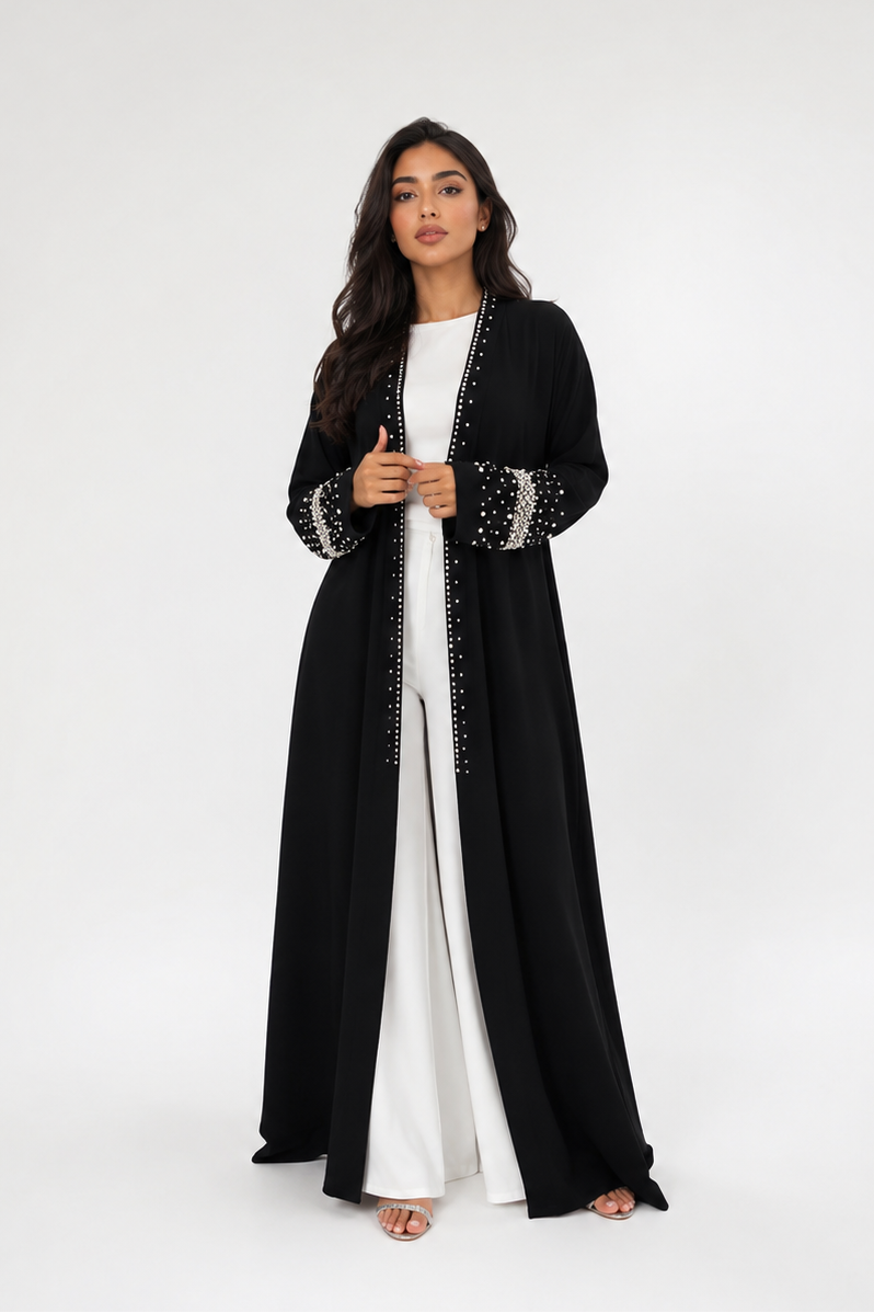 Woman wearing a black abaya with white trim on a white background