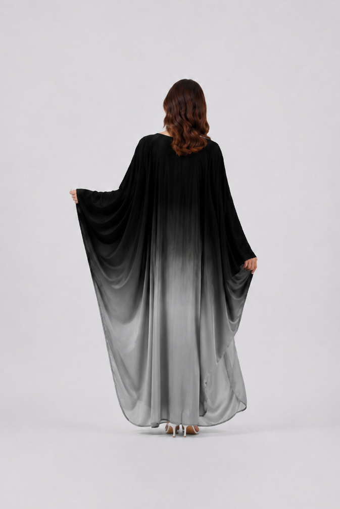 Person wearing a black to gray gradient dress on a white background