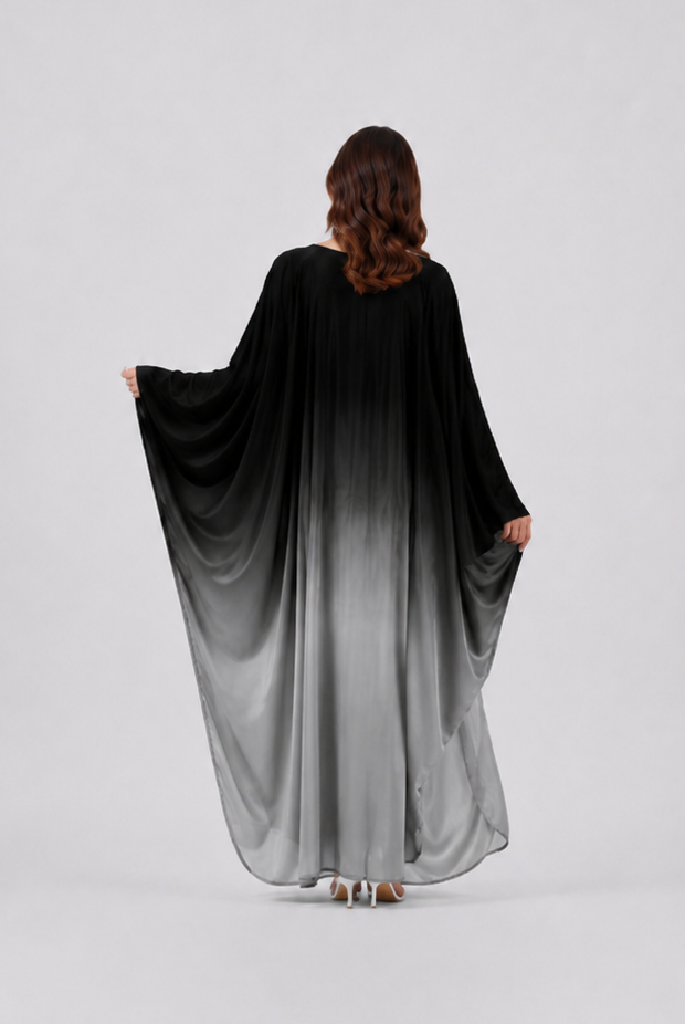 Person wearing a black to gray gradient dress on a white background