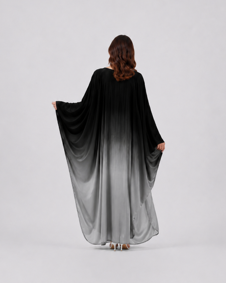 Person wearing a black to gray gradient dress on a white background