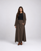 A woman modeling a dark brown long-sleeve wrap maxi skirt with a matching open-front cardigan, worn over a black top and brown ankle boots, against a light gray studio background.