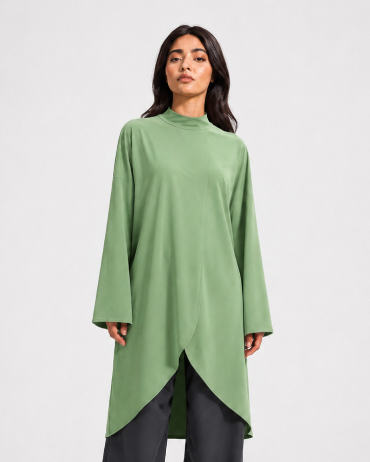 Woman wearing a green long-sleeve top with a high-low hem on a white background