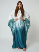 Woman wearing a white and blue gradient dress with a matching shawl on a plain background