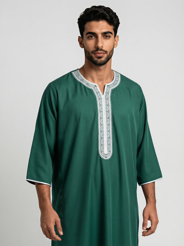 Man wearing a green traditional outfit with white embroidery on a gray background