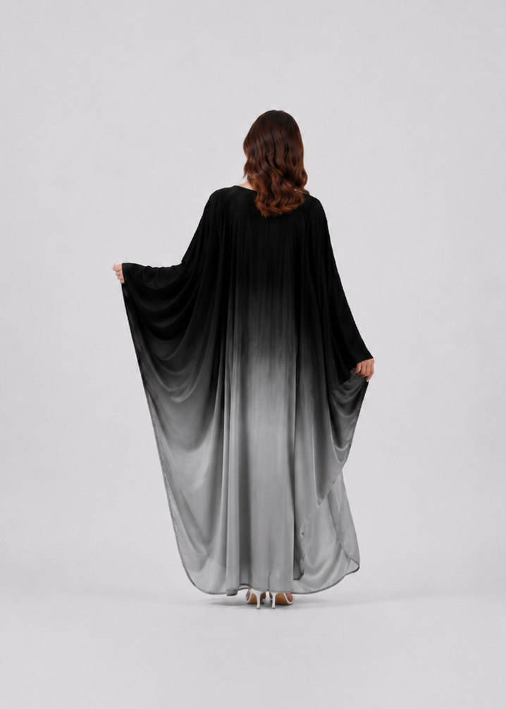 Person wearing a black to gray gradient dress on a white background